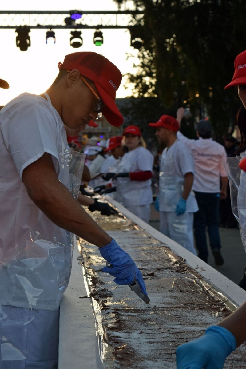 Maestros chocolateros y colaboradores creando la barra m&aacute;s larga del mundo en Bariloche.